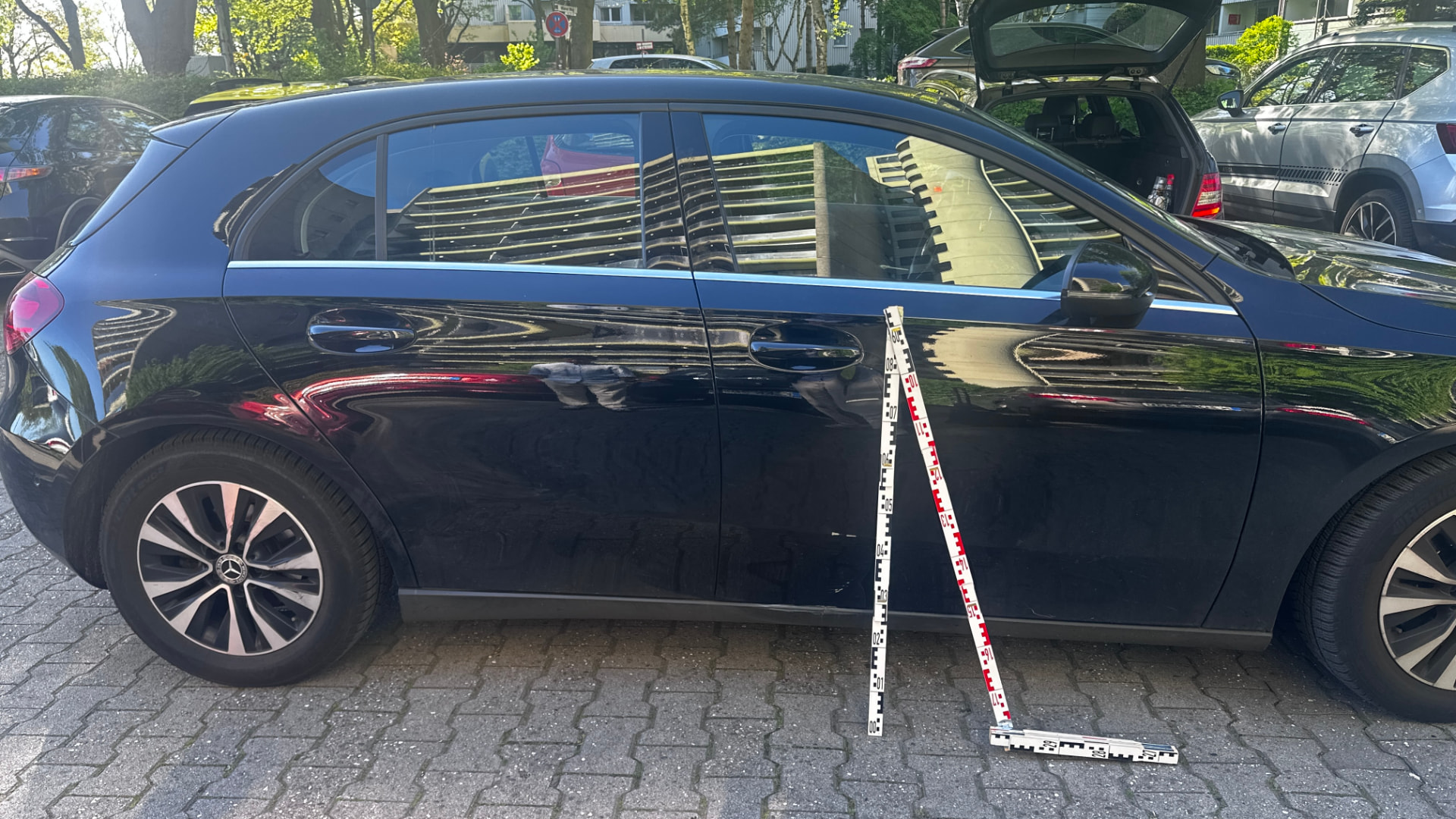 Dokumentierter Seitenschaden an einem schwarzen Mercedes mit Messlatten
